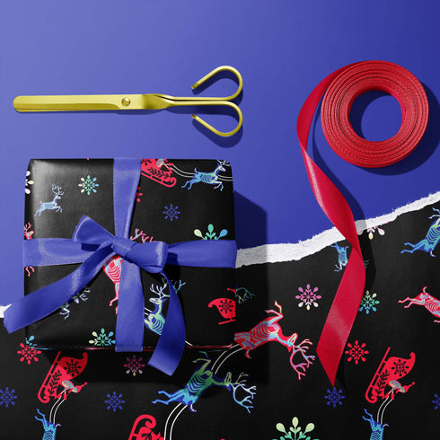Christmas wrapping paper with a black background featuring colorful, stylized reindeer and Santa's sleigh designs. The reindeer and sleigh silhouettes are filled with skeletal patterns in shades of blue, pink, and red. Multicolored snowflakes in various sizes are scattered throughout. The paper has a whimsical, slightly gothic aesthetic that blends traditional holiday imagery with a unique, edgy twist.