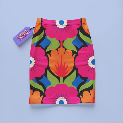 Form-fitting bodycon mini skirt with a mid-rise elastic waistband, falling to mid-thigh in smooth stretch fabric. It features a bold 70s pop art floral print: oversized hot pink flowers with cream scalloped centers, royal blue middles, and fine purple rays, beside a flaming orange tulip, royal blue geometric shapes, and olive green leaves on a black background. The all-over design is a flat dye-sublimated print in vibrant, high-contrast color, available in a smooth knit or glitter knit finish.