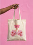 Black 15 x 16 inch 100% cotton tote bag with a kawaii pastel goth cherry-skull design printed on the front. The artwork features two soft pink skulls shaped like cherries, connected by red stems and topped with a bright pink bow. Cute, spooky, coquette, and alt-inspired everyday tote.