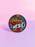 A round embroidered patch with a black background featuring the phrase “STAY WEIRD” in bold, multicolored lettering. "STAY" is stitched in a gradient of red, orange, and yellow, while "WEIRD" is in white. Surrounding the text are wavy, neon-like lines in blue, pink, yellow, and orange, creating a vibrant, psychedelic effect. The patch has a thick black border and is designed for iron-on or sew-on application, making it perfect for jackets, backpacks, denim, and accessories.