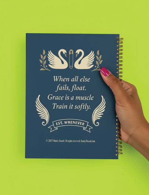 An 8.5 x 11 hardcover spiral planner with a durable satin-matte finish. The front cover is a deep navy blue, featuring elegant cream-colored text and vintage-style illustrations of two swans. A sturdy gold metal wire-o spiral binds the planner on the right side. This undated weekly and monthly goal organizer serves as a motivational journal for women, a self-care tracker, and a funny office supply. The celestial swan design gives it a unique, 70s retro aesthetic for organization.