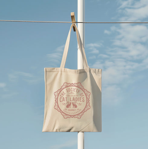 Election 2024 Canvas tote bag featuring a circular design with two cats and text "The Society of Childless Cat Ladies Against Couch Fuckers" in burgundy on a natural or black.