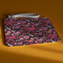 Rectangular wristlet clutch featuring a dark background with pink skull bows, cherries, and other goth-inspired motifs. White strap and gold zipper visible.
