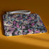 Rectangular wristlet clutch featuring a dark background with colorful bats, skulls, eyeballs, and vampire mouths. White strap and gold zipper visible.