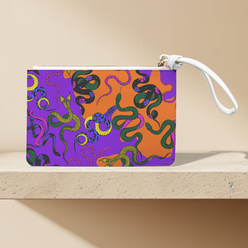 Rectangular wristlet clutch featuring vibrant purple and orange background with colorful snake prints. White strap and gold zipper visible.