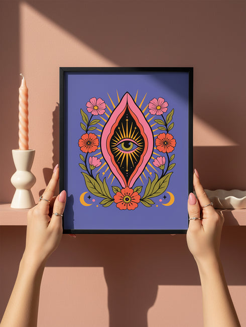 A vertical art print featuring a central pink yoni shape with a black interior containing a single eye. Golden yellow sun rays radiate from the center against a solid periwinkle blue purple background. The central motif is surrounded by a symmetrical botanical border of pink and red daisy flowers and green leaves, with two yellow crescent moons in the bottom corners. Printed on flat museum grade matte paper. This is the printed artwork only; a frame is not included. Ready to frame.