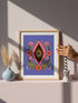 A vertical art print featuring a central pink yoni shape with a black interior containing a single eye. Golden yellow sun rays radiate from the center against a solid periwinkle blue purple background. The central motif is surrounded by a symmetrical botanical border of pink and red daisy flowers and green leaves, with two yellow crescent moons in the bottom corners. Printed on flat museum grade matte paper. This is the printed artwork only; a frame is not included. Ready to frame.