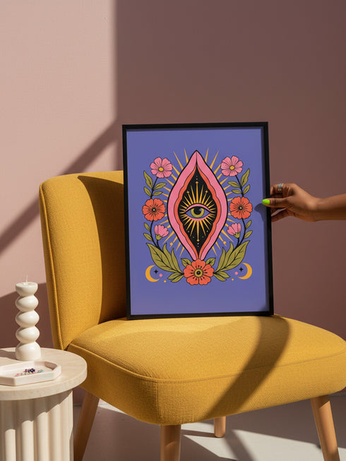 A vertical art print featuring a central pink yoni shape with a black interior containing a single eye. Golden yellow sun rays radiate from the center against a solid periwinkle blue purple background. The central motif is surrounded by a symmetrical botanical border of pink and red daisy flowers and green leaves, with two yellow crescent moons in the bottom corners. Printed on flat museum grade matte paper. This is the printed artwork only; a frame is not included. Ready to frame.