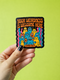 A person holds the Retro Monster Sticker - 70s Groovy Decal | Colorful Monster Art for Self Acceptance, showcasing quirky monster creatures with the message YOUR WEIRDNESS IS WELCOME HERE. Ideal for celebrating individuality and neurodiversity.