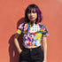 A colorful 90s-style mesh crop top featuring a maximalist abstract pattern. This see-through shirt has a high mock neck, short sleeves, and a vibrant, retro design with geometric shapes, color blocking, and polka dots in bold shades of pink, yellow, blue, and orange. The Y2K-inspired top is a statement piece of festival clothing, perfect for a rave outfit or alternative, dopamine-dressing-inspired streetwear looks.
