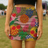 A woman wearing a colorful, patterned mini skirt with various fruits and floral designs.