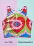 A sleeveless scoop neck crop top featuring a bold all-over printed design. The central graphic is a large bright red heart enclosing a scalloped pink flower shape and a blue evil eye motif in the middle. The background surrounds the heart with mirrored concentric wavy arches and scalloped borders in vibrant shades of lime green, pink, blue, and red. The fitted garment has a smooth athletic texture. Available in a standard matte performance knit or a sparkly silver glitter foil finish.