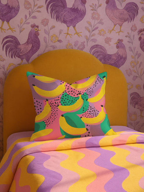 Colorful square pillow cover featuring a bold banana print in yellow, pink, green, purple, and black. The print appears on both sides and is made of luxe polyester with a linen-like texture. Hidden zipper closure. Available in two sizes: 22x22 inches and 18x18 inches. Designed for bright, dopamine-style, maximalist home decor.