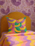 Colorful square pillow cover featuring a bold banana print in yellow, pink, green, purple, and black. The print appears on both sides and is made of luxe polyester with a linen-like texture. Hidden zipper closure. Available in two sizes: 22x22 inches and 18x18 inches. Designed for bright, dopamine-style, maximalist home decor.