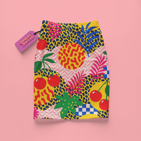 A colorful skirt with a vibrant pattern of fruits, flowers, and geometric shapes against a pink background.