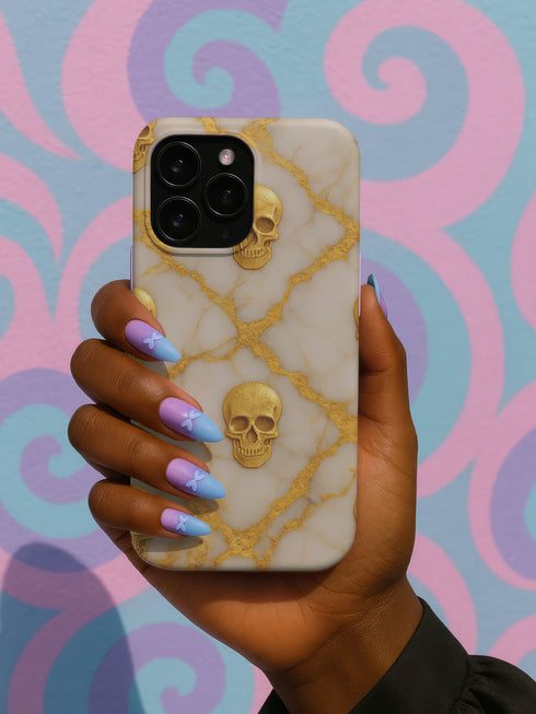 A hand holding a phone case with a skull design against a colorful background.
