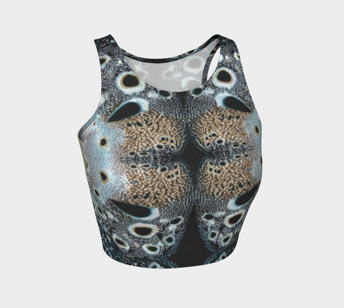 A women's sleeveless racerback crop top with a body-hugging fit. The top features a detailed, kaleidoscopic all-over print inspired by deer pelt. The symmetrical, Rorschach-like design includes abstract spots and textures in shades of brown, blue, black, and grey, creating an intricate pattern that resembles a deer pelt.