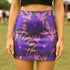 High waisted mini skirt with bold purple and pink floral print in a vibrant, maximalist style. Features a sculpted, body-hugging fit with a 1.5-inch elastic waistband that sits comfortably at the natural waist. Made from eco polyester and spandex blend that is stretchy, quick-drying, odor-resistant, and includes UPF 50 UV protection. Available in standard or glittery metallic finish in sizes S to XL.