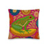 A square decorative throw pillow made from premium polyester with a visible linen-like woven texture. The background is a vibrant hot pink covered in a dense, retro-style floral pattern in orange, teal, and gold. The main design is a brightly colored, stylized illustration of a green red-eyed tree frog with orange feet and prominent red eyes. The whimsical frog is riding a vibrant yellow banana. The overall aesthetic is colorful, maximalist, and eclectic, with a faux-embroidered texture effect.