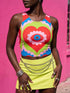 A sleeveless scoop neck crop top featuring a bold all-over printed design. The central graphic is a large bright red heart enclosing a scalloped pink flower shape and a blue evil eye motif in the middle. The background surrounds the heart with mirrored concentric wavy arches and scalloped borders in vibrant shades of lime green, pink, blue, and red. The fitted garment has a smooth athletic texture. Available in a standard matte performance knit or a sparkly silver glitter foil finish.