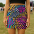 A woman wearing a colorful, patterned mini skirt stands in a grassy field.