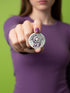Round pinback button featuring a pastel mint green background with a cartoon grim reaper character in a lavender hood holding a protest sign. The design includes bold black outlined lettering reading “Pacifist Reaper” above the figure and small sparkle accents surrounding it. The finish is glossy and smooth, with a printed illustration style on a metal pin badge surface.