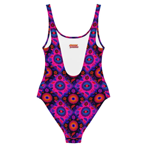 Bold patterned one-piece swimsuit with retro evil eye floral design, styled in festival-ready outdoor settings. Swimsuit features a scoop neckline, cheeky fit, and low scoop back. Ideal for summer vacations, pool parties, raves, and alt girl fashion. Made from stretchy, moisture-wicking fabric with UPF 50+ protection. Available in sizes XS to 3X. Colorful, statement swimwear designed for confident, maximalist style lovers.