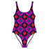 Bold patterned one-piece swimsuit with retro evil eye floral design, styled in festival-ready outdoor settings. Swimsuit features a scoop neckline, cheeky fit, and low scoop back. Ideal for summer vacations, pool parties, raves, and alt girl fashion. Made from stretchy, moisture-wicking fabric with UPF 50+ protection. Available in sizes XS to 3X. Colorful, statement swimwear designed for confident, maximalist style lovers.