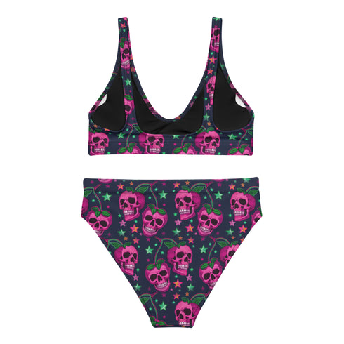 Two-piece bikini set featuring a bold pastel goth design with neon pink skulls wearing green bows, surrounded by multicolored stars on a deep black background. The set includes a plunging V-neck bikini top with wide straps and high-waisted bottoms for a flattering retro fit. Made of stretchy, soft material with a smooth black lining. This skull print swimsuit is ideal for alternative, edgy summer style with a playful punk twist.