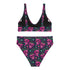 Two-piece bikini set featuring a bold pastel goth design with neon pink skulls wearing green bows, surrounded by multicolored stars on a deep black background. The set includes a plunging V-neck bikini top with wide straps and high-waisted bottoms for a flattering retro fit. Made of stretchy, soft material with a smooth black lining. This skull print swimsuit is ideal for alternative, edgy summer style with a playful punk twist.