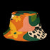 Reversible unisex bucket hat featuring two distinct retro-inspired designs - one side showcases a vibrant 70s-style floral pattern with large orange and yellow flowers, green leaves, and black polka dot accents on cream and coral backgrounds, while the reverse side displays a sophisticated brown and beige floral pattern with orange blooms and neutral tones. Made from 100% polyester with textured linen feel, this moisture-wicking and breathable hat is available in XS, S/M, and L/XL sizes, perfect for vintage