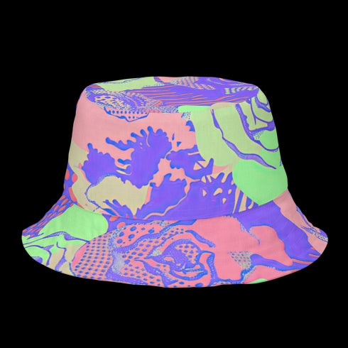 Reversible unisex bucket hat featuring two distinct designs - one side showcases a vibrant floral pop art pattern with purple, pink, green and blue splashes and organic flower motifs, while the reverse side displays a purple giraffe print pattern with dark purple giraffe spots on a light purple background. Made from 100% polyester with textured linen feel, this moisture-wicking and breathable hat is available in XS, S/M, and L/XL sizes for ultimate style versatility.
