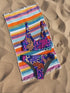 Psychedelic animal print bikini top with multicolor tiger pattern in neon pink, purple, orange, and blue, made of stretchy recycled fabric with wide shoulder straps and scoop neckline.
