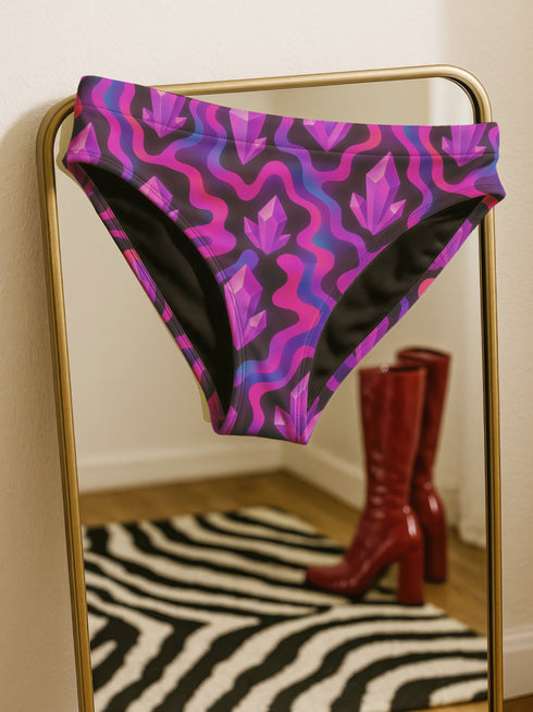 High-waisted bikini bottom with a psychedelic crystal pattern in purple, magenta, and black, featuring cheeky cut and four-way stretch fabric with a moisture-wicking finish.