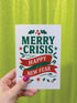 A 5x7 alternative holiday card with a white background and bold, punk-inspired typography. The text reads "Merry Crisis Happy New Fear" in dark green and red. The design features graphic elements like holly, stars, and safety pins, giving it a sarcastic, goth aesthetic. The inside message says "Consider this card your coping mechanism." This snarky, dark humor greeting card is perfect for a funny, unconventional Christmas, capturing a mental health humor and anti-capitalist vibe.