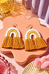 a pair of yellow and white tassel earrings with fringed tassels, displayed on a pink speckled surface.