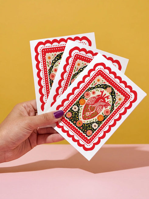 Realistic anatomical heart illustration printed in high contrast ink on a premium 5x7 inch shimmery pearlescent greeting card. The biological heart drawing features detailed arteries, veins, and ventricles, styled with a vintage medical or folk art aesthetic. The cardstock has a visible iridescent sheen. Blank inside valentine card shown with a white peel and seal envelope. Perfect for gothic decor, medical student gifts, cardiology nurse appreciation, and dark academia stationery collections.