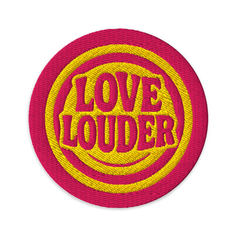 A round, 3-inch embroidered Love Louder patch designed with a vibrant, retro 70s aesthetic. The design features groovy, puffy-style text in a bright, sunny yellow thread, set against a bold magenta pink twill fabric background. The words 'LOVE LOUDER' are stacked to fill the center, encircled by concentric yellow rings that create a hypnotic, radiating effect. The entire circular patch is finished with a clean, durable merrowed border.