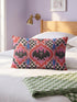 Rectangular 20x12 inch lumbar pillow cover in red featuring printed faux embroidery of three black bats with white eyes and pink noses, each framed in an ornate ogee medallion with pink flame stitch centers, black and white checkerboard accents, and cobalt blue diamonds. Whimsigoth damask bat design printed on both sides with a hidden zipper, crafted from soft linen look polyester for spooky maximalist home decor.