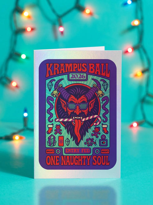 A vertical 5x7 inch folded greeting card featuring a detailed, psychedelic illustration of the folklore figure Krampus for a New Year celebration. The card stock has a shimmering pearlescent finish that reflects light, creating a glowing effect on the purple and teal artwork. The design mimics a vintage event poster reading "Krampus Ball 2026" and "Entry Fee: One Naughty Soul" in retro fonts. Krampus is depicted with large horns, sunglasses, and a long tongue holding a candy cane.