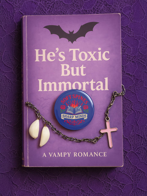 A round pinback button in blue with a glossy mylar face and metal construction. The design, in a traditional tattoo style, features a central open book with flames rising from its pages. Two silver swords with black hilts are crossed over the book. On either side of the book is a red rose with a green stem and leaves. Below the book is a cream-colored banner with the words "SHARP MINDS" in a black serif font. Above the book, the words "SOFT SPINES" are written in a curved, red font.