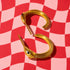 a pair of gold snake-shaped earrings with black stones on a red and white checkered background.