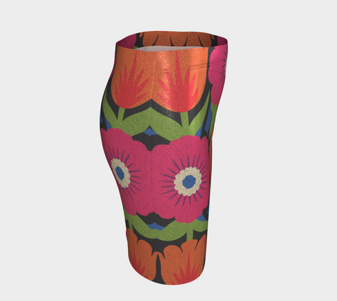 Form-fitting bodycon mini skirt with a mid-rise elastic waistband, falling to mid-thigh in smooth stretch fabric. It features a bold 70s pop art floral print: oversized hot pink flowers with cream scalloped centers, royal blue middles, and fine purple rays, beside a flaming orange tulip, royal blue geometric shapes, and olive green leaves on a black background. The all-over design is a flat dye-sublimated print in vibrant, high-contrast color, available in a smooth knit or glitter knit finish.