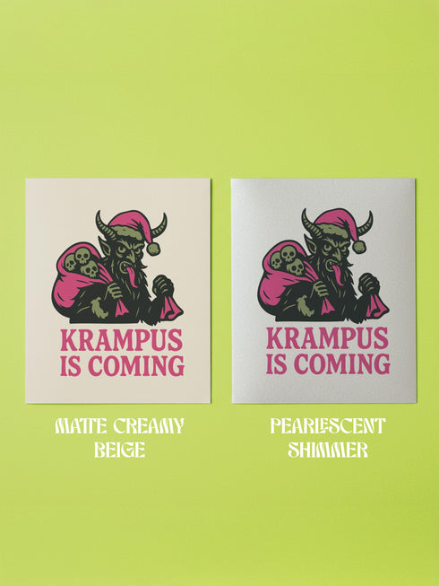 A 5x7 inch Krampus Christmas card shown in two paper finishes. The front features a stylized illustration of the folklore demon Krampus with green skin, black horns, and a pink Santa hat. He carries a large pink sack filled with three skulls over his shoulder. Below him, the words "KRAMPUS IS COMING" are printed in bold pink text. The inside of the card is blank on the left and has the printed text "Hope you've been beautifully bad this year." on the right.