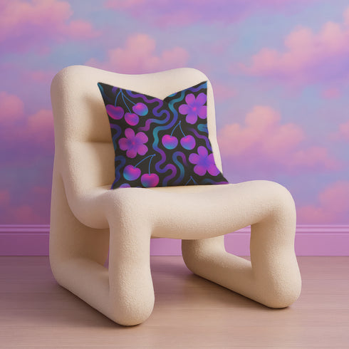 Square throw pillow with a black background featuring a psychedelic pattern of bright pink cherries, purple hibiscus flowers, and wavy teal and magenta lines. Design is bold, colorful, and maximalist.