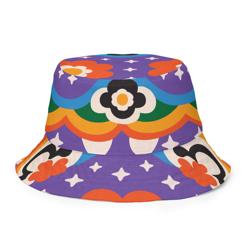 A reversible bucket hat with two distinct sides. Side one features a red and yellow zebra pattern with large pink and orange daisies. Side two has a deep purple background with white stars, rainbow scalloped bands in blue, green, and orange, and retro black and white flowers. The fabric has a visible textured linen weave. The hat is shown in a structured, professional studio shot against a white background, highlighting its 100% polyester durability.
