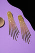 a pair of gold dangling earrings with a sparkling crystal design, placed on a purple background.