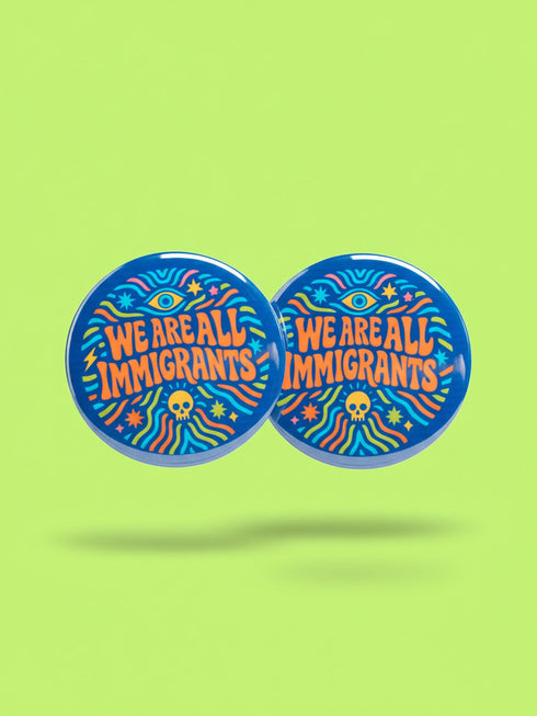 A round 1.75 inch blue pinback button featuring retro psychedelic artwork. The text reads We Are All Immigrants in a groovy orange and red 1970s font style centered on the badge. A mystic third eye sits above the text while a small skull sits below it. Wavy rainbow lines in cyan, green, and orange radiate outward from the center along with small starbursts and lightning bolts. The button has a glossy finish reflecting light.