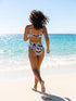 A two piece recycled high waisted swimsuit with a pastel goth checkered print in light lavender purple, pale mint green, and white squares with black cow print spots. The design features small black hearts and silhouetted bats with outspread wings printed throughout. The athletic style crop top has a deep scoop neck and matching thick straps, while the double layered bottoms have a supportive high waistband and cheeky cut with a solid black inner lining.
