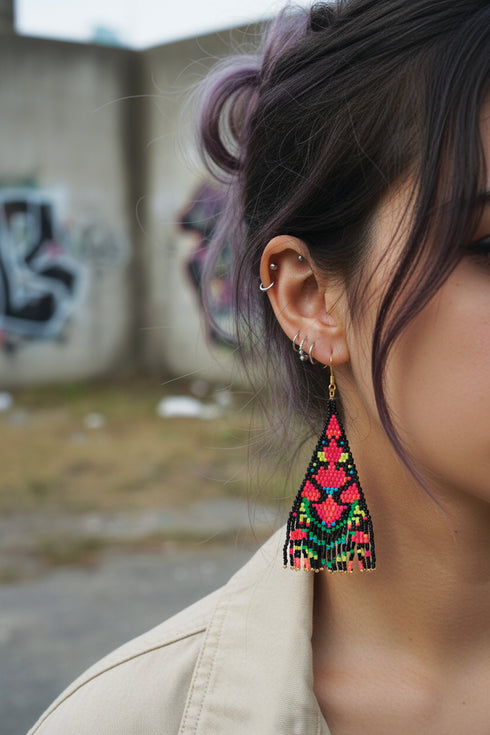 A close-up of a person's ear with a colorful, beaded earring hanging from it.